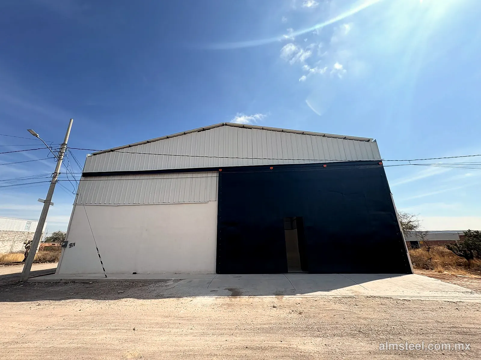Fachada de la bodega terminada, con lámina en el frontón y portón negro